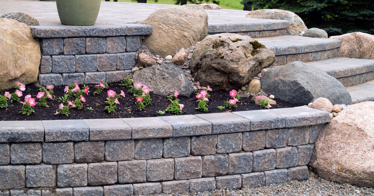 Natural stone retaining wall, flower garden, and boulders
